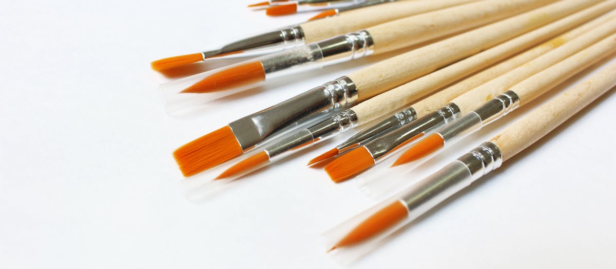 A set of wooden-handle paintbrushes with orange bristles arranged on a white background.