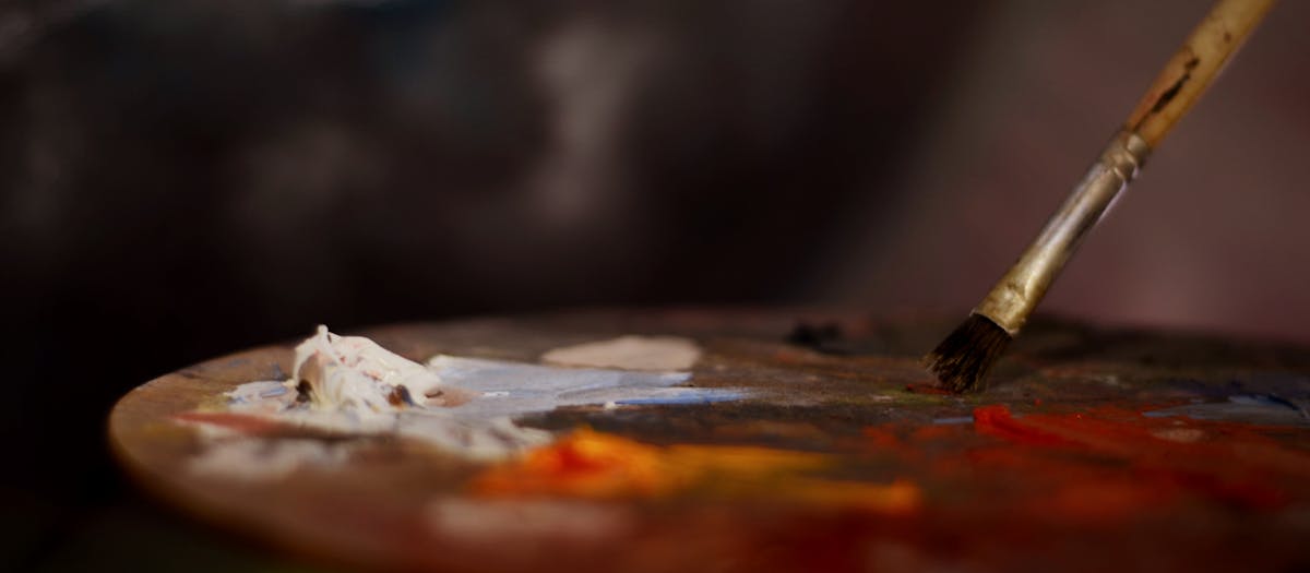 Close-up of an artist's palette with vibrant paints and a brush for creative expression.